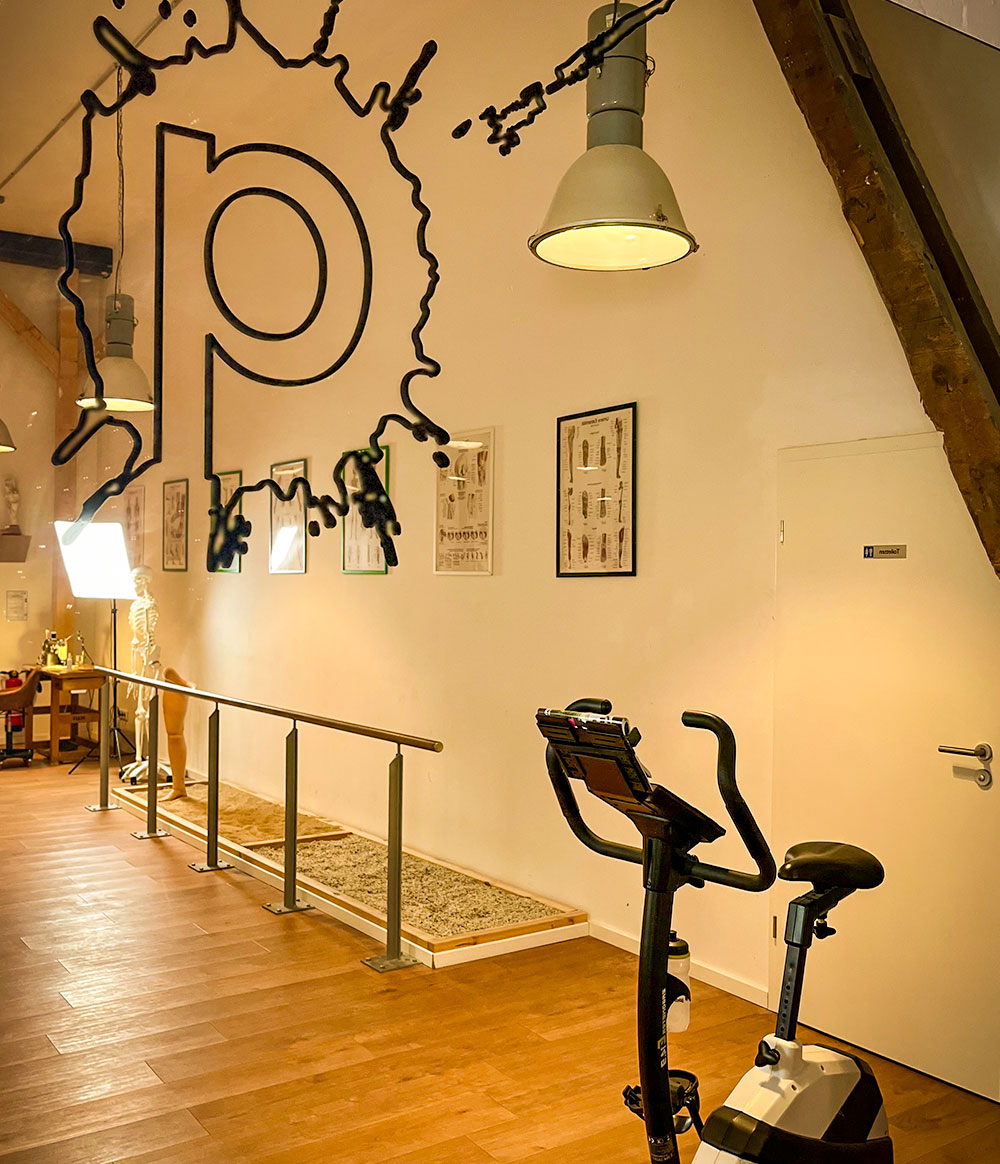 Trainingsbereich mit Gehbarren über Sandkasten und Trimmrad in der Orthopädiewerkstatt von Frank Purk in Hamburg